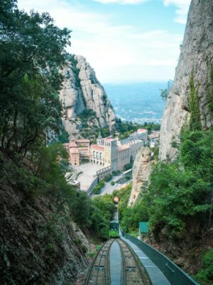 A breathtaking view of Montserrat Monastery nestled between mountains with a cable railway leading up.